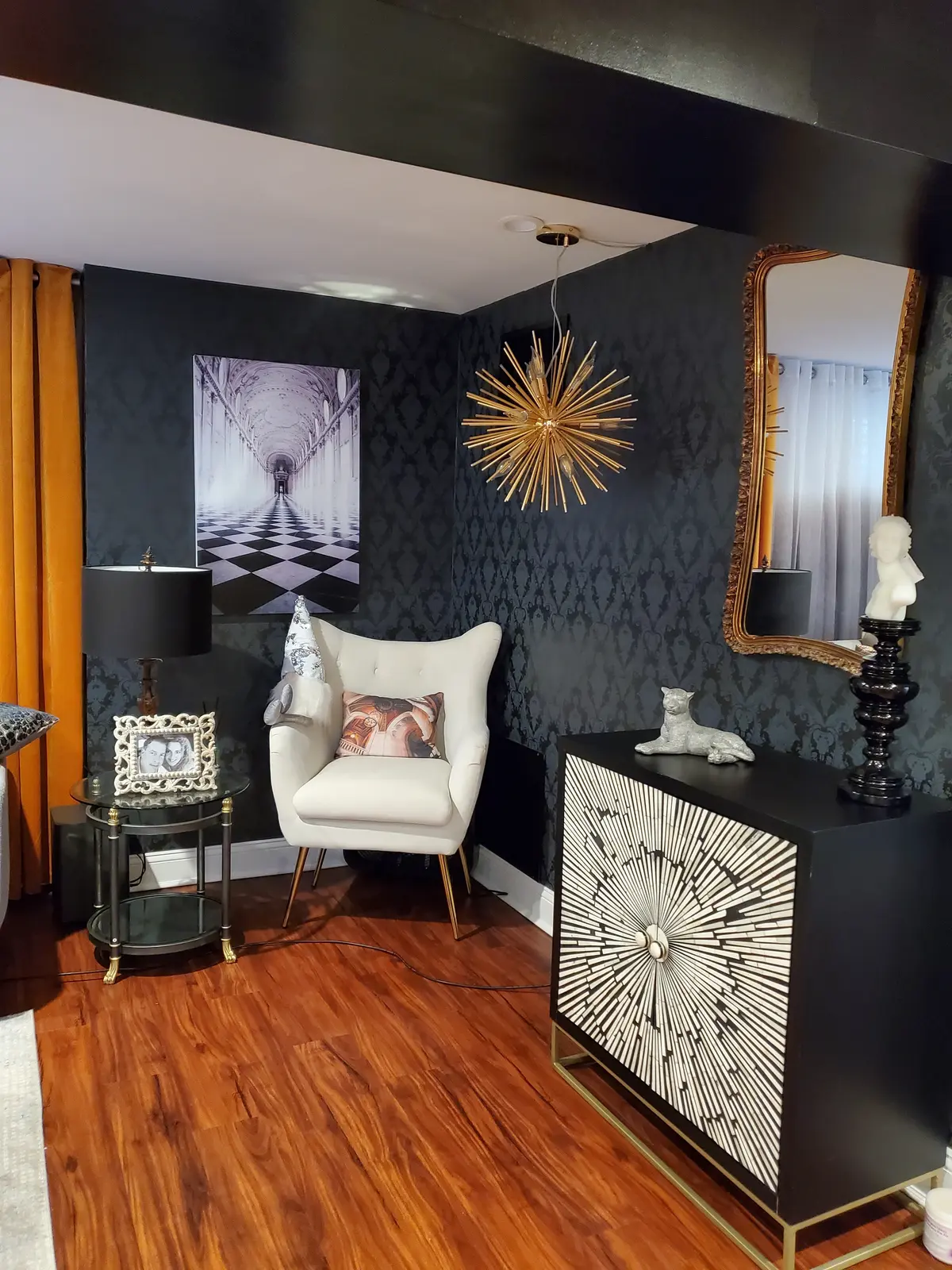 Dramatic black and gold sitting room with damask wallpaper and sunburst cabinet — designed by Renata Glaz